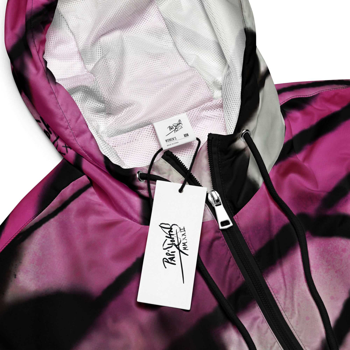 Close-up detail view highlighting the raw black spray paint splatter, high-definition blush pink gradient transition, and custom PapiJohn® brand tagging on the SALA 3 | Attitude Crop Pink Fade Windbreaker by $arah Free 💎. Honest luxury streetwear curated in Cadifornia.