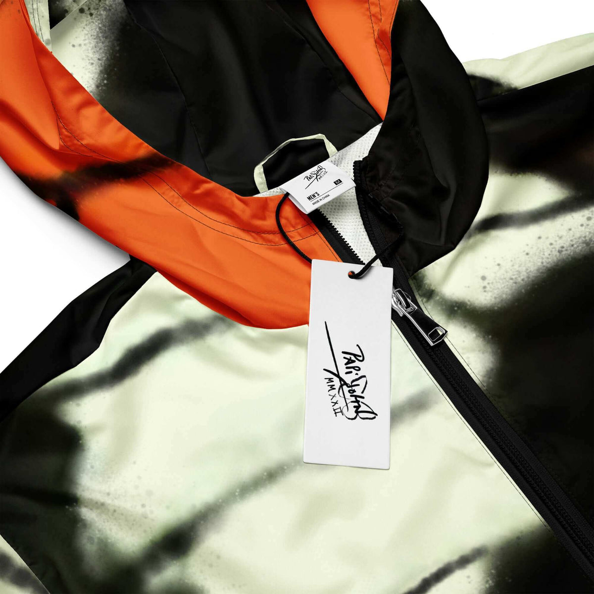 Close-up detail view highlighting the custom PapiJohn® brand tag, heritage orange monarch wing print texture, and custom hardware on the SALA 3 | Attitude Monarca Origin Windbreaker by $arah Free 💎. Honest luxury studio gear curated in Cadifornia.