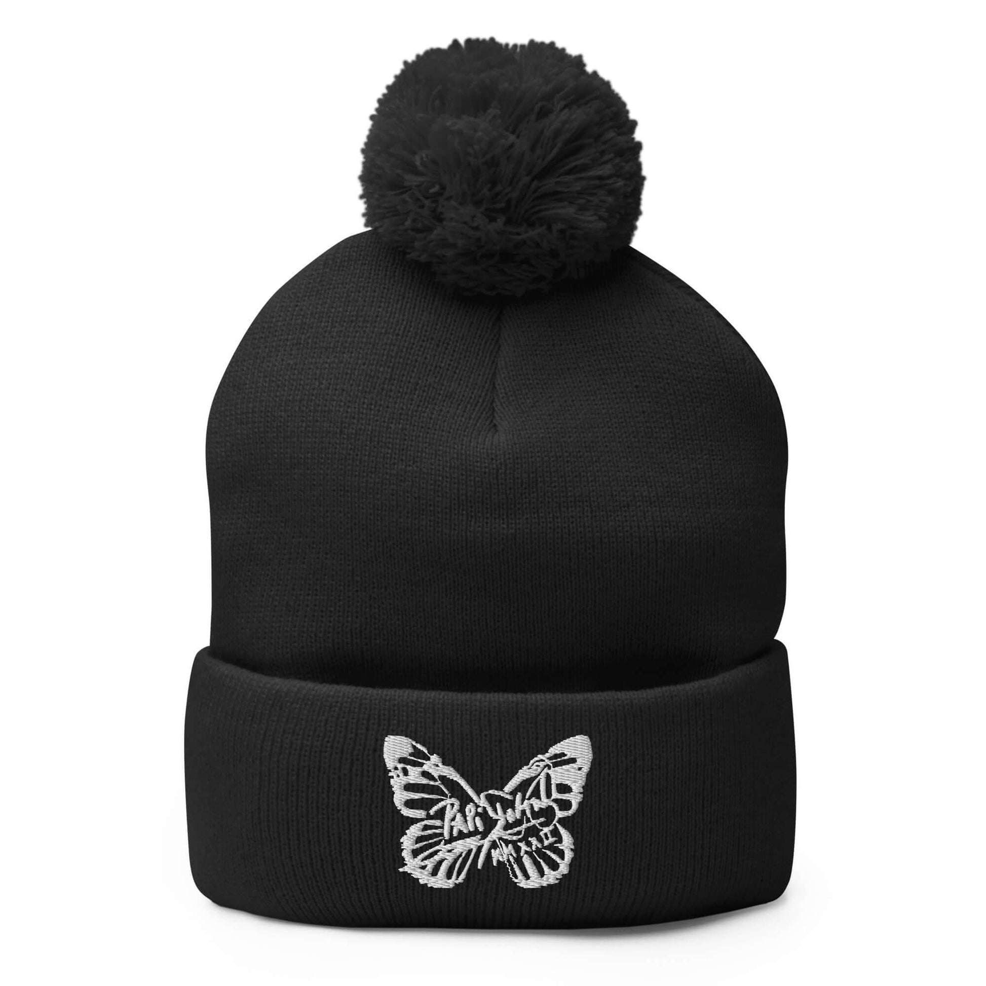 PapiJohn® The White Butterfly Pom-Pom Beanie in solid black front view showcasing the pristine pure white thread butterfly motif embroidered in heavy high density by $arah Free 💎 | Sala 1 Wearable Art Fashion