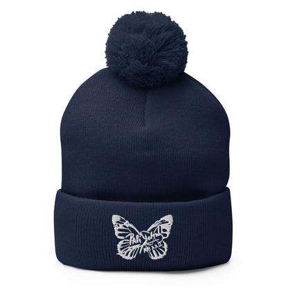 PapiJohn® The White Butterfly Pom-Pom Beanie in deep navy blue front view highlighting the crisp white embroidered butterfly icon contrast over the structured rib knit | Artist-Led Streetwear