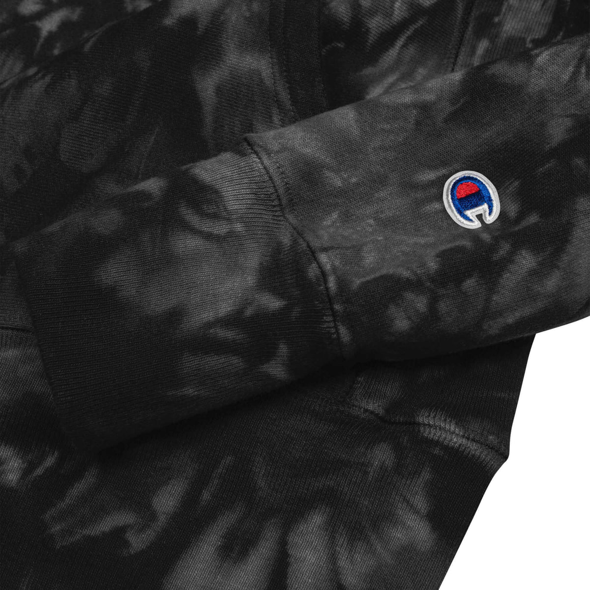 PapiJohn® 🏛️ Sala 5 | The Tie-Dye Reverse | Champion® Heritage — Close-up sleeve detail of the Black Tie-Dye Hoodie. Highlighting the iconic Champion® "C" logo embroidery on the left sleeve, perfectly sealing the collaboration between legendary athletic heritage and the authentic PapiJohn® Cadifornia movement.